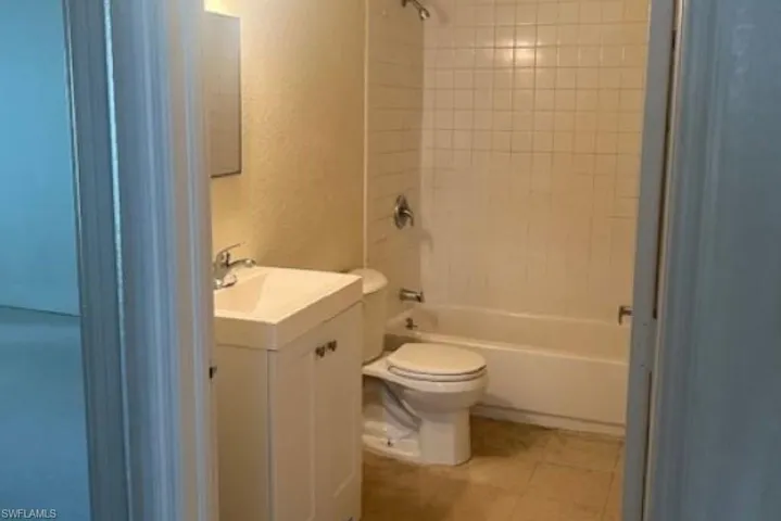 Full bathroom featuring tile flooring, vanity, toilet, and tiled shower / bath combo