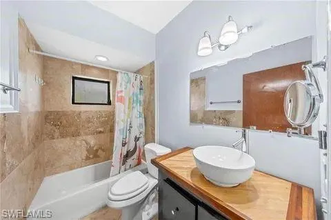 Bathroom with shower / bathtub combination with curtain and vanity