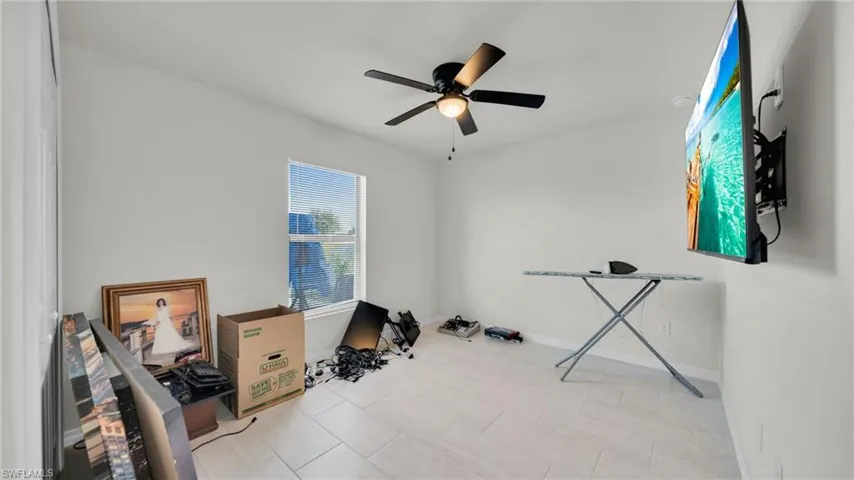 Workout room featuring a ceiling fan and light tile patterned floors