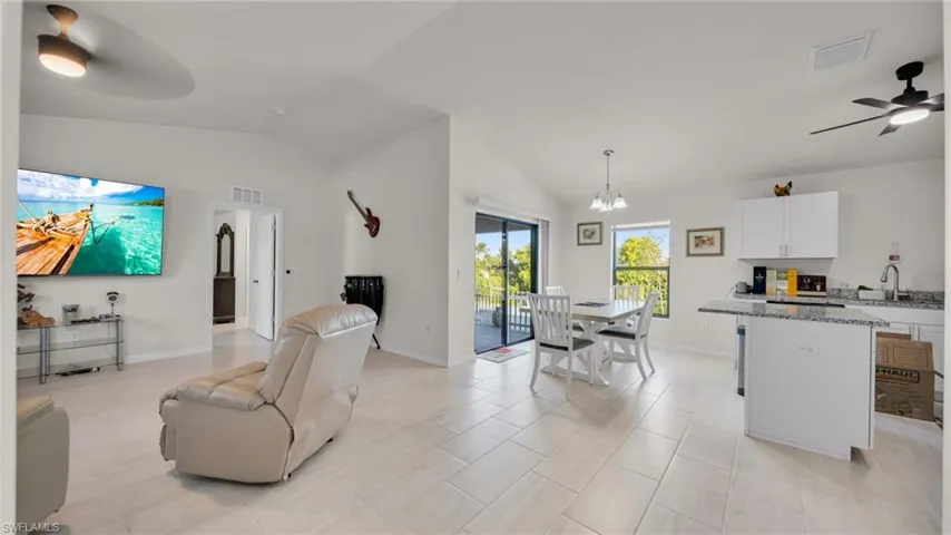 Living area featuring a ceiling fan, lofted ceiling, a chandelier, and light tile patterned flooring