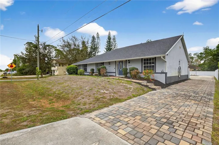 Single story home with decorative driveway, stucco siding, roof with shingles, and a porch