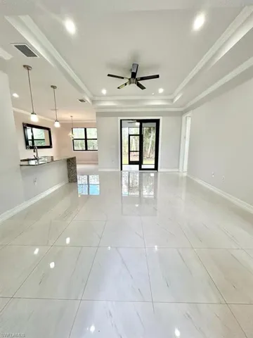 Empty room with recessed lighting, a raised ceiling, crown molding, and a ceiling fan