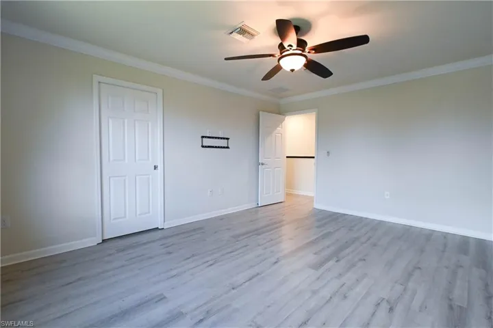 Unfurnished room featuring ceiling fan, ornamental molding, and light hardwood / wood-style flooring