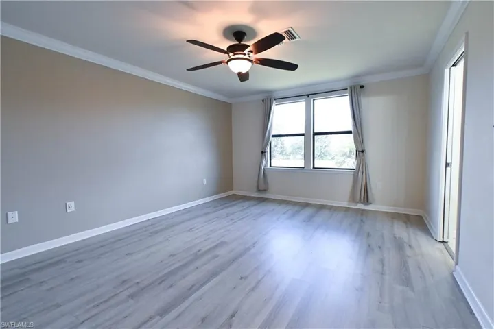 Spare room with crown molding, light hardwood / wood-style flooring, and ceiling fan