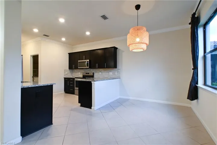 Kitchen with a healthy amount of sunlight, backsplash, light stone counters, and appliances with stainless steel finishes