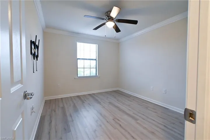 Spare room with light wood-type flooring, ornamental molding, and ceiling fan