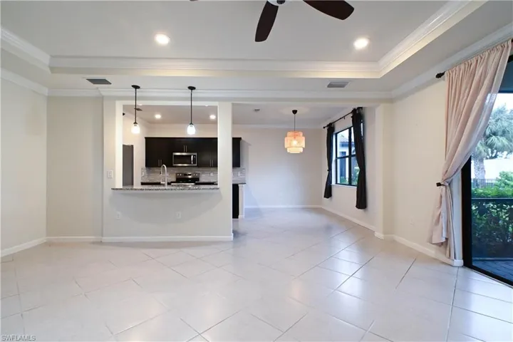 Unfurnished living room featuring ceiling fan, light tile patterned floors, crown molding, and sink