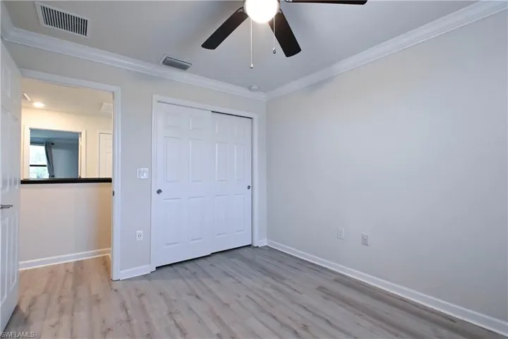 Unfurnished bedroom with crown molding, light hardwood / wood-style flooring, ceiling fan, and a closet