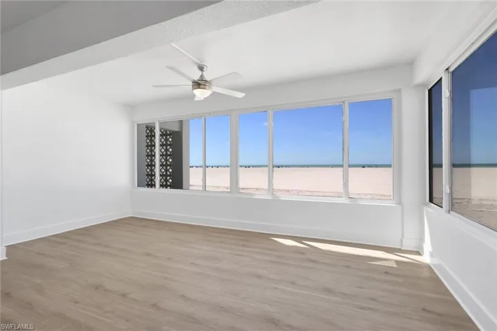 Empty room with a ceiling fan, light wood-type flooring, and a water view
