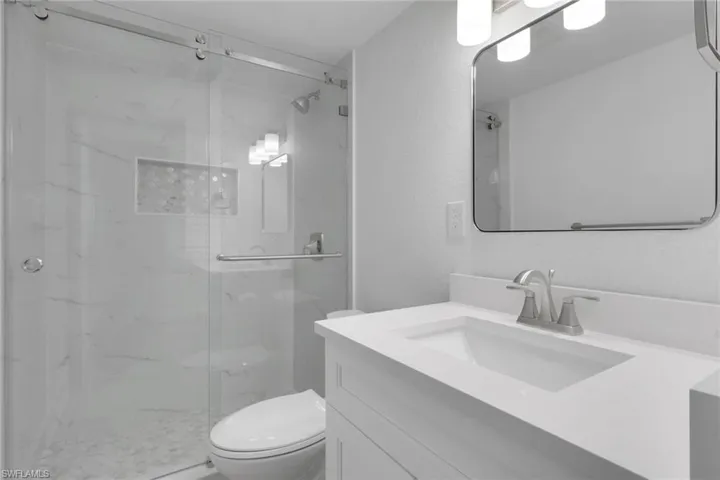 Bathroom with vanity, a marble finish shower, and a textured wall