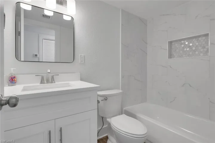 Bathroom with vanity, a textured wall, and shower / tub combination