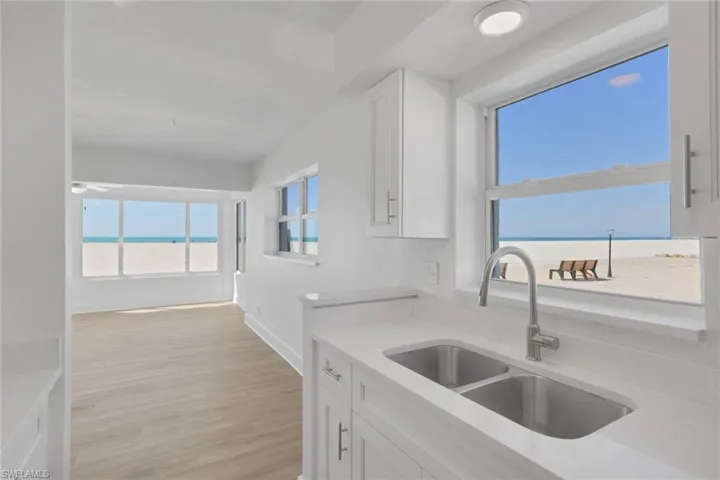 Kitchen with white cabinets, light stone counters, light wood-style floors, and a water view
