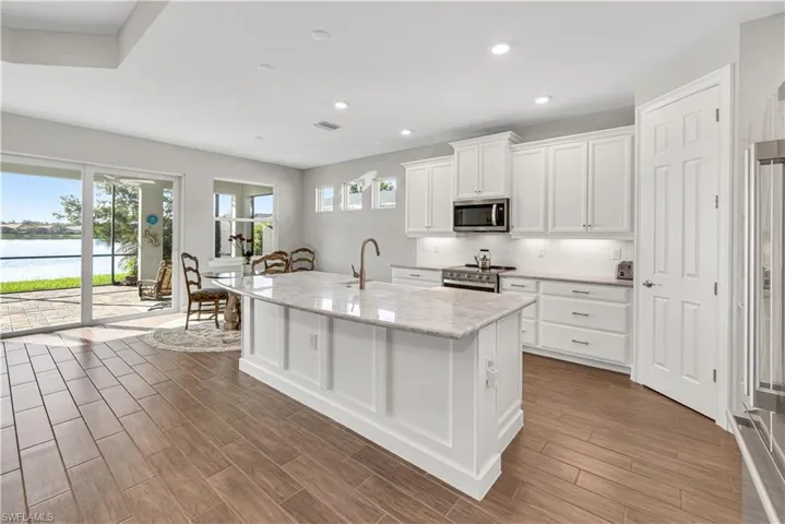 Kitchen with appliances with stainless steel finishes, white cabinets, tasteful backsplash, a water view, and light stone counters