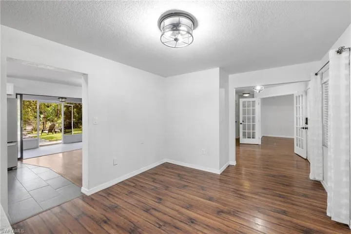 Unfurnished room featuring a textured ceiling, dark hardwood / wood-style flooring, and french doors