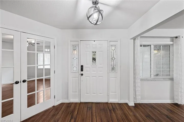 Entrance foyer featuring french doors, dark wood-type flooring, and a textured ceiling