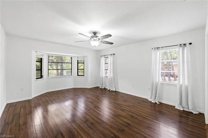 Empty room featuring ceiling fan, dark hardwood / wood-style flooring, and a textured ceiling