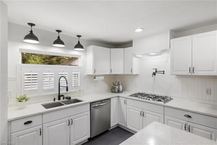 Kitchen with white cabinets, appliances with stainless steel finishes, pendant lighting, and sink