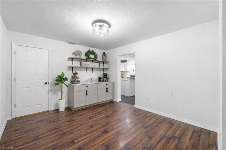 Bar with white cabinets, dark hardwood / wood-style floors, and a textured ceiling