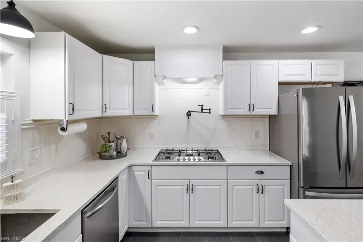 Kitchen with white cabinetry, pendant lighting, and stainless steel appliances
