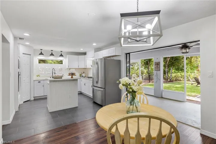 Kitchen with white cabinets, a kitchen island, dark wood-type flooring, and stainless steel refrigerator