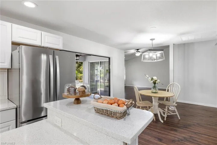 Kitchen with white cabinets, stainless steel fridge, dark hardwood / wood-style flooring, and light stone countertops