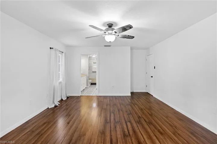Empty room featuring ceiling fan and dark wood-type flooring