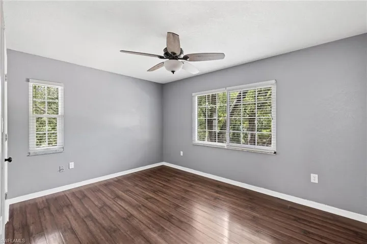 Spare room with dark hardwood / wood-style flooring, plenty of natural light, and ceiling fan