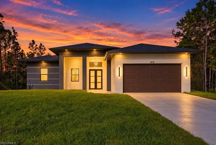 Modern single-story exterior featuring a multi-tone facade, recessed entryway, double glass-panel front door, and attached two-car garage
