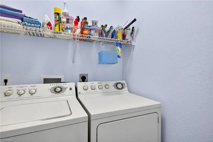 Laundry room with a textured wall and washing machine and clothes dryer