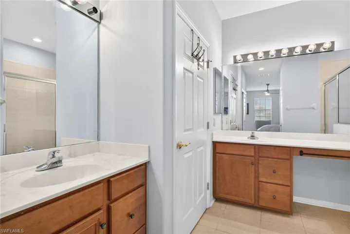 Bathroom featuring two vanities, ensuite bathroom, a stall shower, and light tile patterned flooring