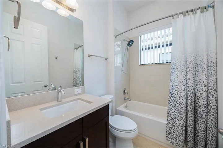 Full bathroom with tile patterned floors, vanity, shower / bath combo, and toilet