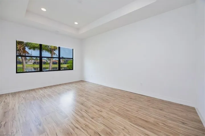 Unfurnished room featuring light wood-type flooring and a tray ceiling