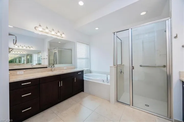 Bathroom featuring tile patterned flooring, vanity, and separate shower and tub