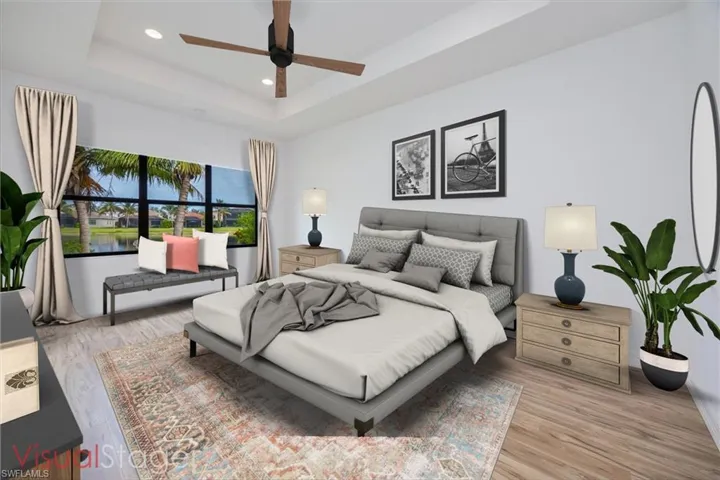 Bedroom featuring ceiling fan, a raised ceiling, and light hardwood / wood-style flooring