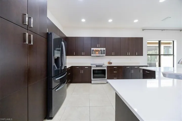 Kitchen featuring appliances with stainless steel finishes, dark brown cabinetry, light tile patterned floors, and sink