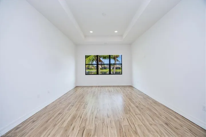 Spare room featuring a raised ceiling and light hardwood / wood-style floors