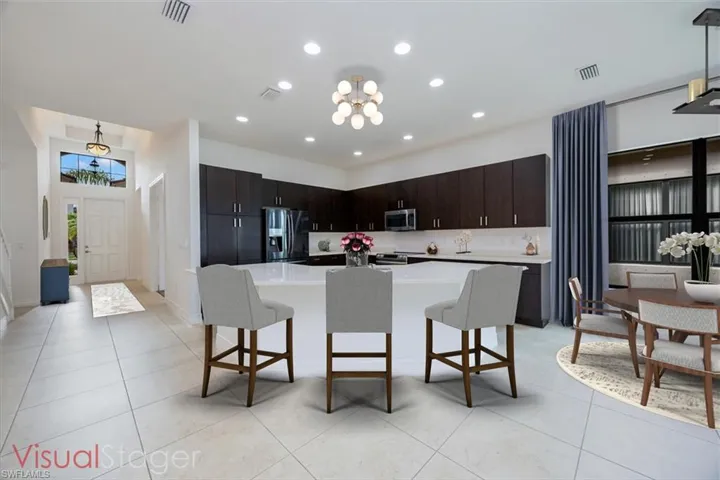 Kitchen with appliances with stainless steel finishes, dark brown cabinetry, an inviting chandelier, a center island, and a breakfast bar area