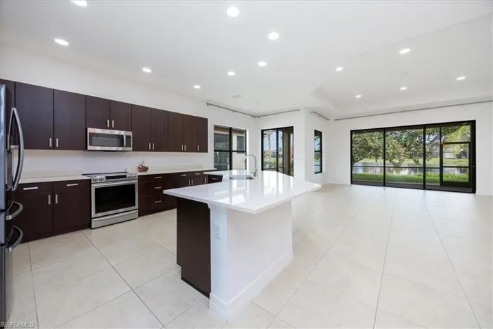 Kitchen featuring a healthy amount of sunlight, light tile patterned flooring, an island with sink, and appliances with stainless steel finishes