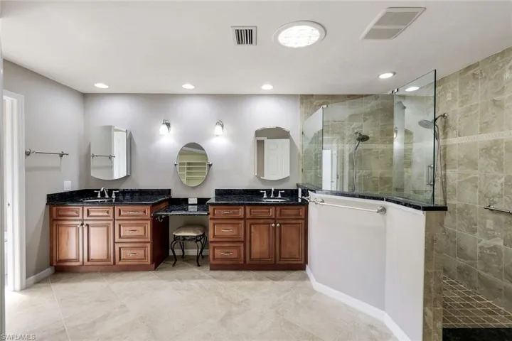 Bathroom featuring tiled shower and vanity