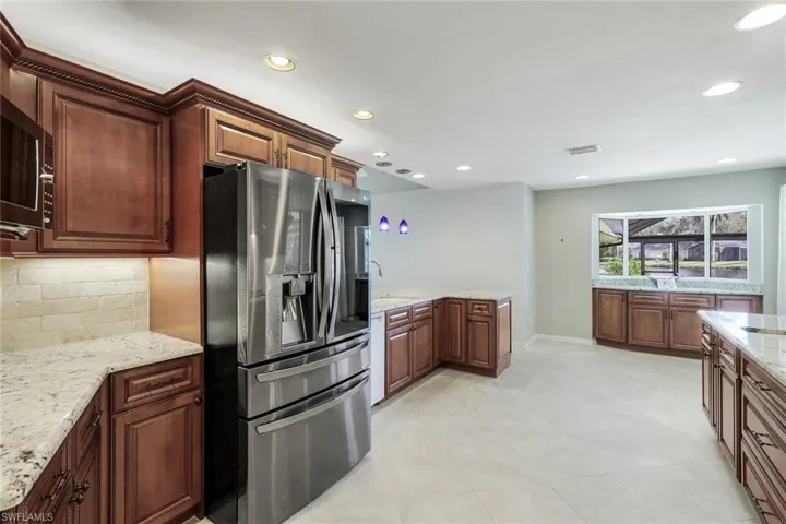 Kitchen with decorative backsplash, stainless steel appliances, Two sinks, and light granite countertops
