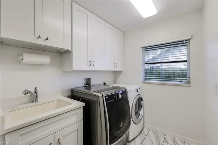 Clothes washing area featuring cabinets, sink, and separate washer and dryer