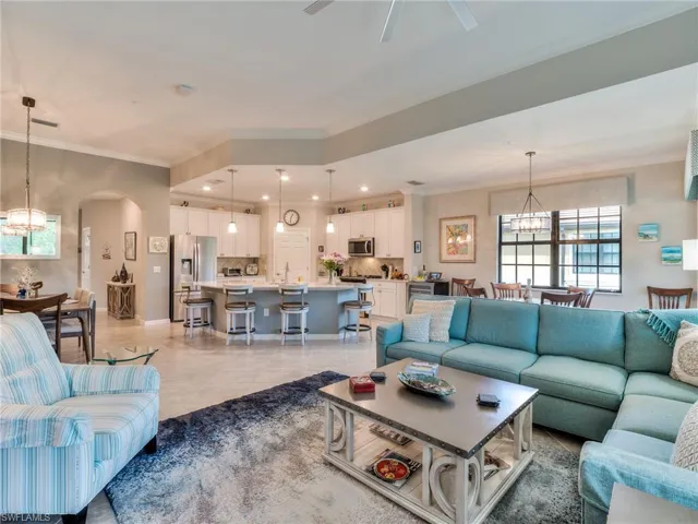 Tiled living room with ceiling fan with notable chandelier and crown molding