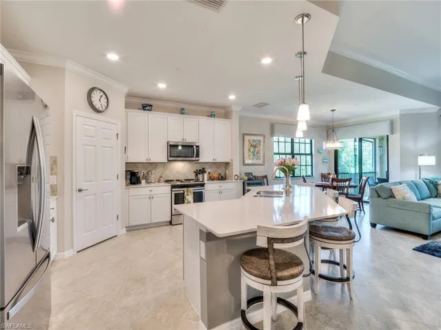 Kitchen with white cabinets, stainless steel appliances, a kitchen breakfast bar, a kitchen island with sink, and sink