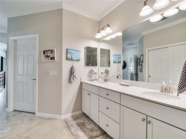Bathroom featuring dual bowl vanity, tile floors, and crown molding