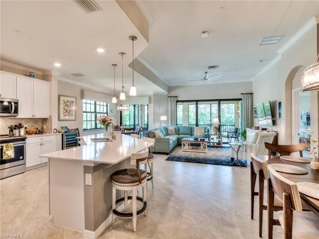 Kitchen with white cabinetry, a kitchen breakfast bar, stainless steel appliances, a kitchen island with sink, and ceiling fan
