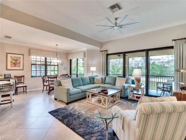 Living room featuring ceiling fan, ornamental molding, and light tile floors