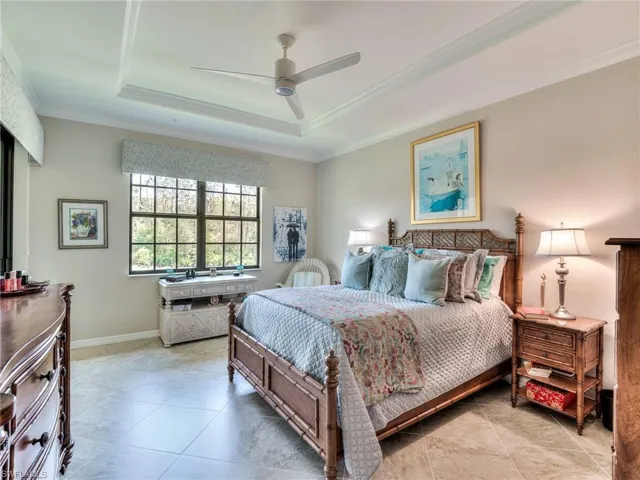 Bedroom with tile floors, ceiling fan, a raised ceiling, and ornamental molding