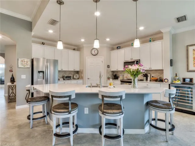 Kitchen with stainless steel appliances, sink, a large island, and tasteful backsplash