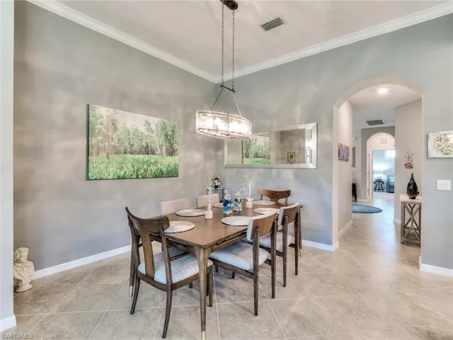 Tiled dining space featuring a notable chandelier and crown molding