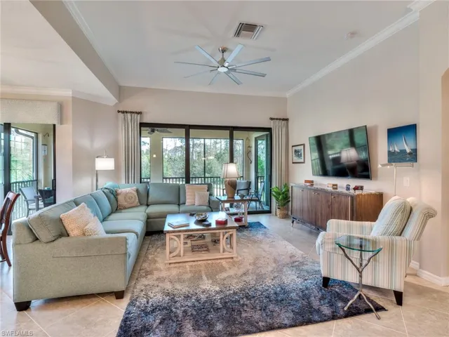 Living room with ornamental molding, ceiling fan, and light tile flooring